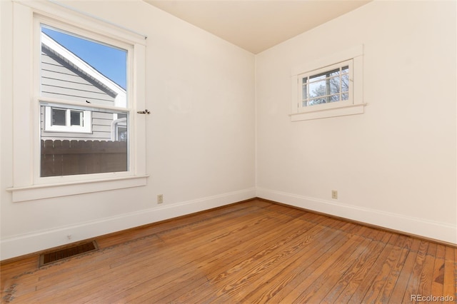 spare room with light wood-style flooring, visible vents, and baseboards