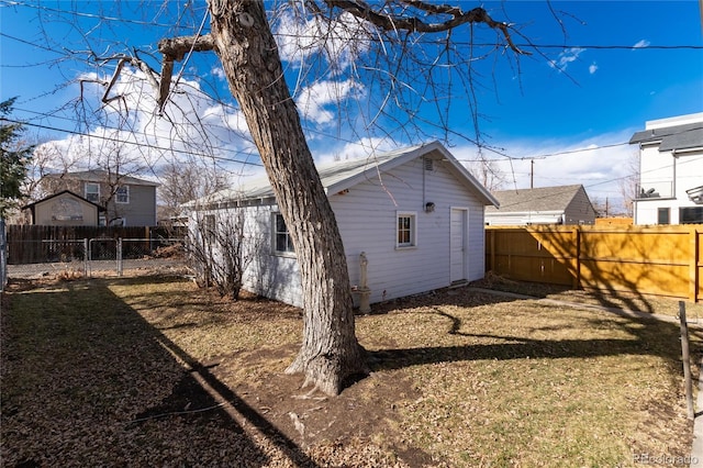 back of house with an outbuilding, a lawn, and a fenced backyard