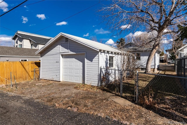 exterior space featuring a garage, driveway, fence, and an outdoor structure