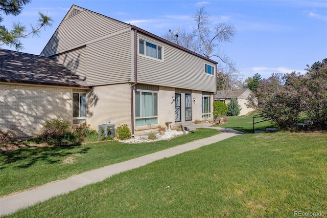 back of property with brick siding, a yard, and cooling unit