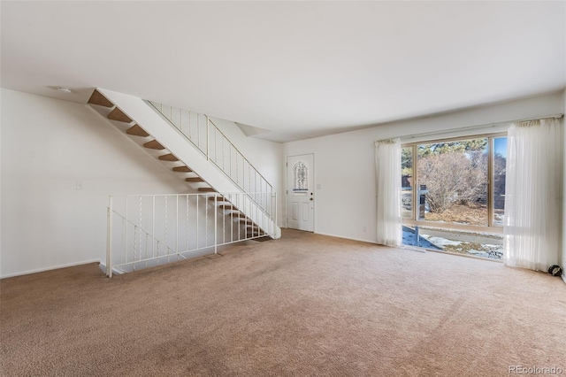 unfurnished living room with stairway, carpet flooring, and baseboards