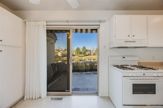 kitchen with visible vents, under cabinet range hood, gas range gas stove, and white cabinetry
