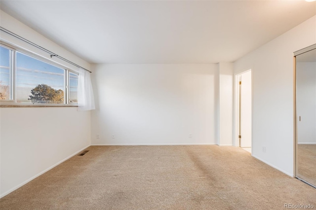 unfurnished room with baseboards, carpet flooring, and visible vents