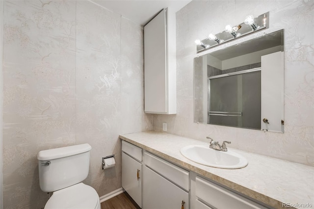 bathroom featuring toilet, vanity, wood finished floors, and a stall shower