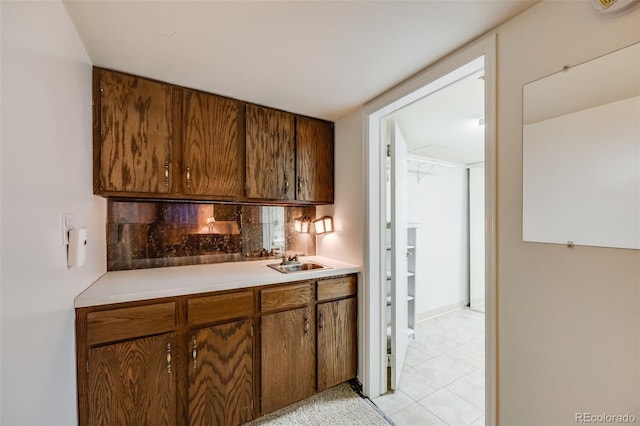 bar with light tile patterned floors, decorative backsplash, and a sink