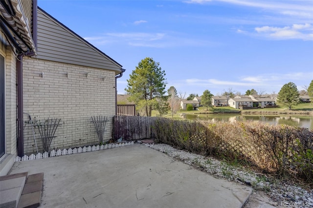 view of patio / terrace featuring fence, a water view, and a residential view
