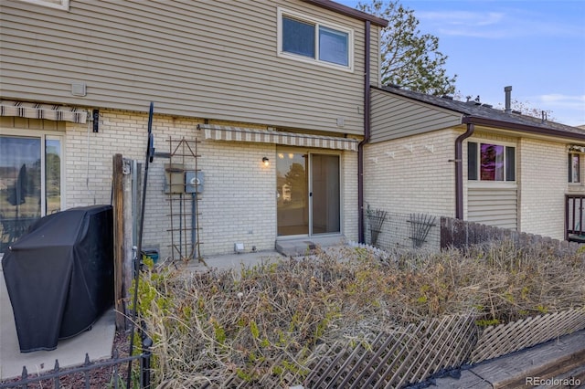 back of house featuring brick siding and fence