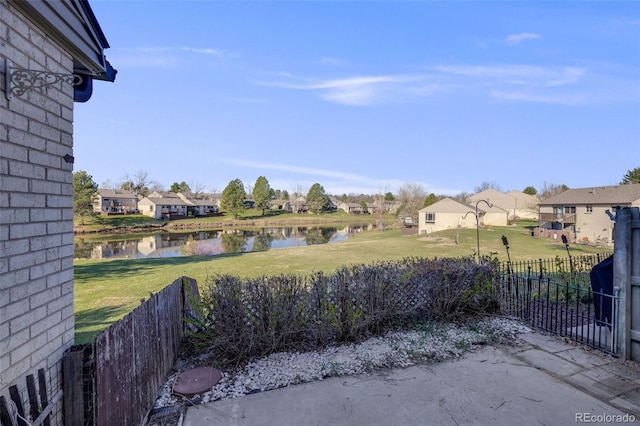 view of yard with a residential view, a water view, and fence