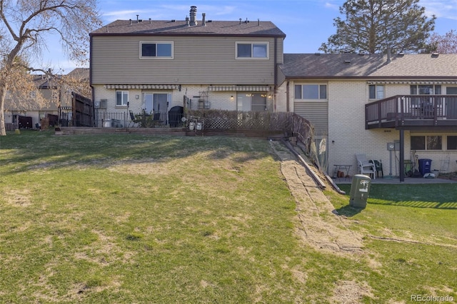 back of house with a wooden deck, brick siding, and a yard