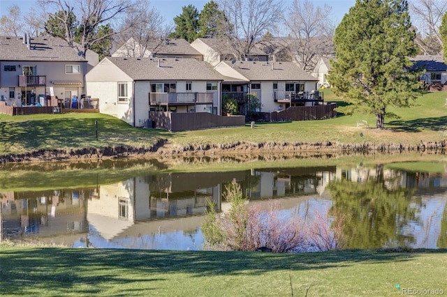 rear view of house featuring a lawn, central air condition unit, a water view, and a residential view