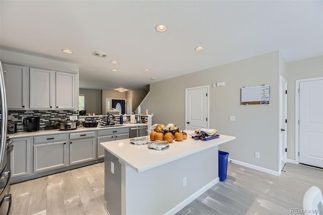 kitchen with tasteful backsplash, stainless steel dishwasher, light wood-type flooring, and a kitchen island