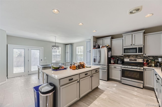 kitchen with a kitchen island, appliances with stainless steel finishes, pendant lighting, and plenty of natural light