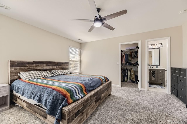 bedroom with ceiling fan, a spacious closet, a closet, ensuite bath, and light colored carpet