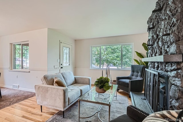 living room with a stone fireplace and wood-type flooring