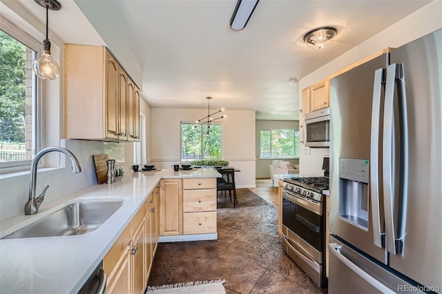 kitchen featuring stainless steel appliances, pendant lighting, sink, and light brown cabinets