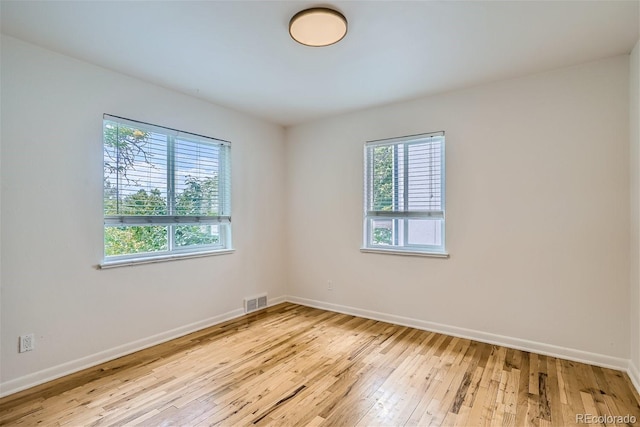 empty room with plenty of natural light and light hardwood / wood-style flooring