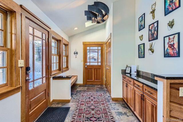 doorway to outside featuring vaulted ceiling and plenty of natural light