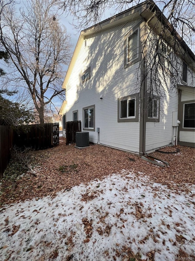 snow covered rear of property with cooling unit