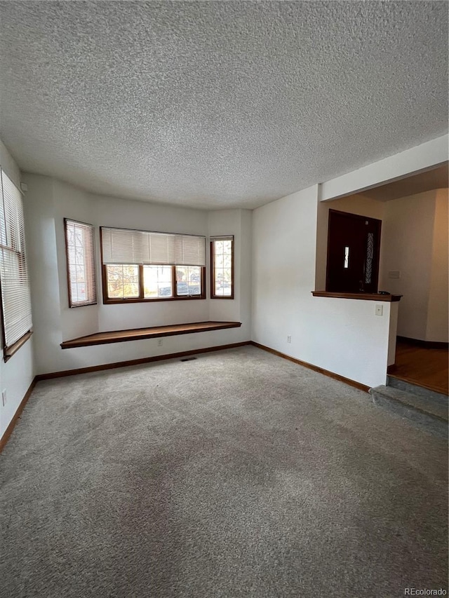 unfurnished living room with carpet flooring and a textured ceiling