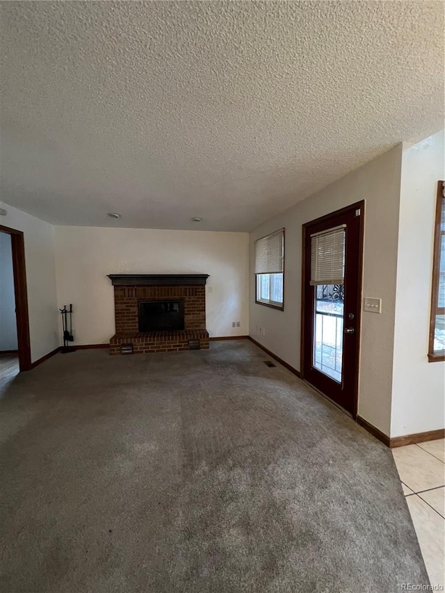 unfurnished living room featuring a textured ceiling, light carpet, and a brick fireplace