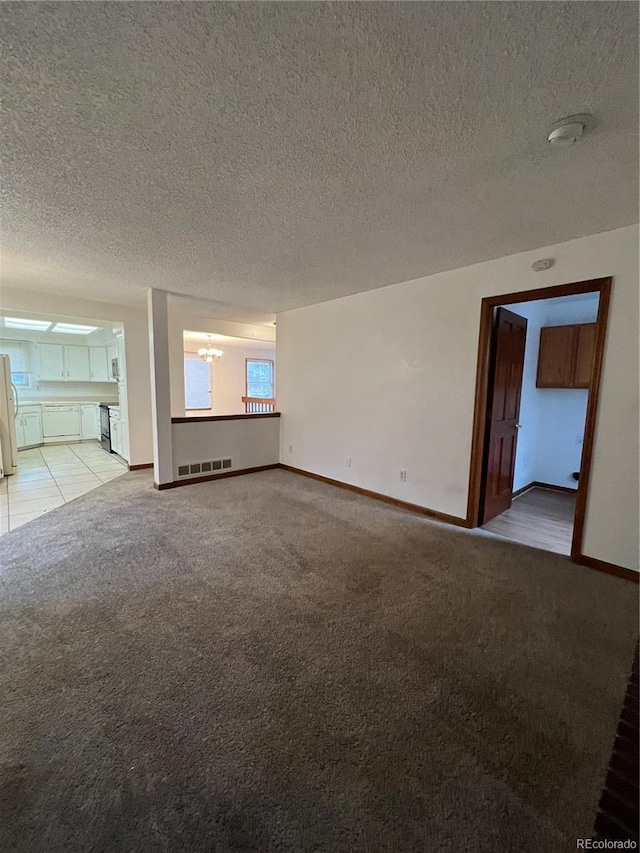 unfurnished living room with light carpet, a textured ceiling, and a notable chandelier