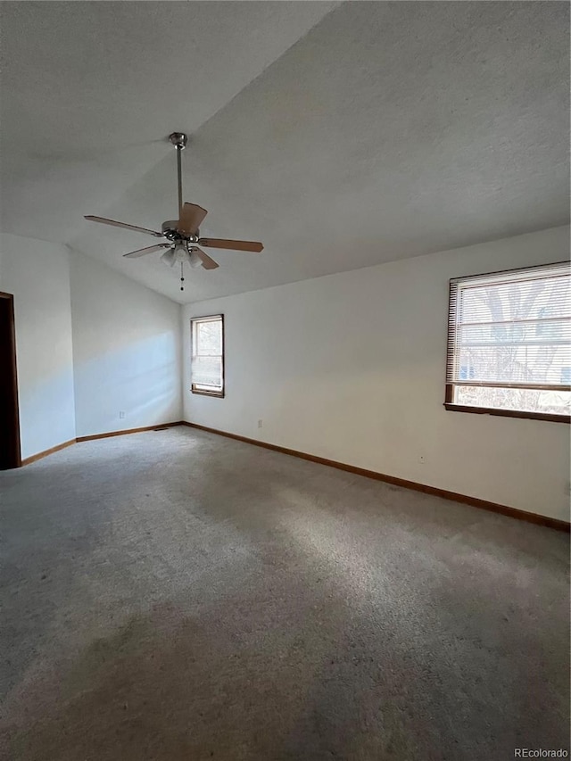 carpeted empty room with plenty of natural light, ceiling fan, a textured ceiling, and vaulted ceiling