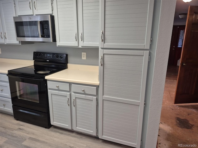 2477 S Oakland Cir, Aurora, CO 80014 - kitchen featuring stainless steel microwave, black range with electric stovetop, light countertops, and light wood-style floors