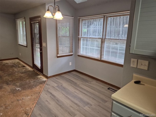 2477 S Oakland Cir, Aurora, CO 80014 - unfurnished dining area featuring a chandelier, healthy amount of natural light, and baseboards