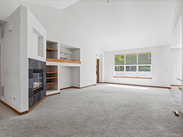 7254 S Kellerman Way, Aurora, CO 80016 - unfurnished living room featuring built in shelves, carpet flooring, a tiled fireplace, and high vaulted ceiling