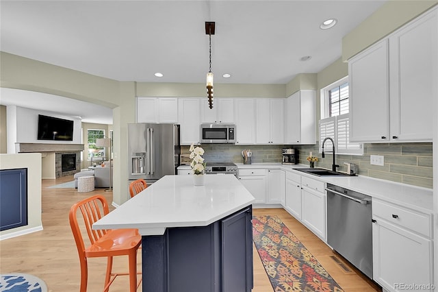 7064 E 2nd Ave, Denver, CO 80220 - kitchen with stainless steel appliances, a sink, decorative backsplash, a breakfast bar, and a kitchen island