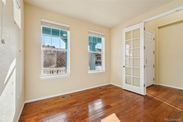 unfurnished room featuring visible vents, baseboards, french doors, and hardwood / wood-style flooring