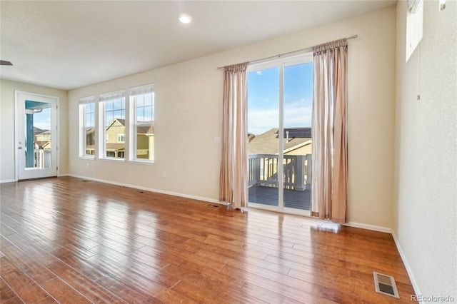 empty room featuring visible vents, baseboards, and wood finished floors