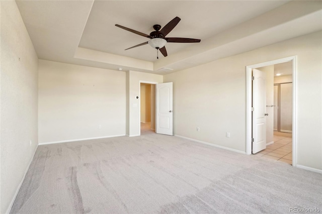 unfurnished bedroom with baseboards, a raised ceiling, carpet floors, and ensuite bathroom