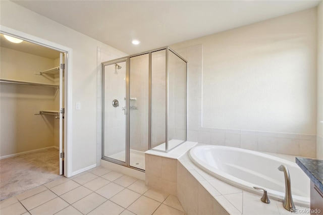 bathroom with a garden tub, a spacious closet, a stall shower, and tile patterned floors