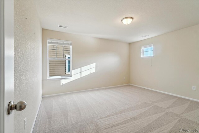 unfurnished room with visible vents, baseboards, and carpet floors