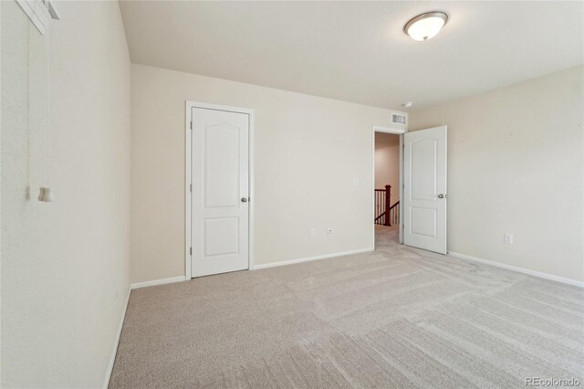 unfurnished bedroom with baseboards, light carpet, and visible vents