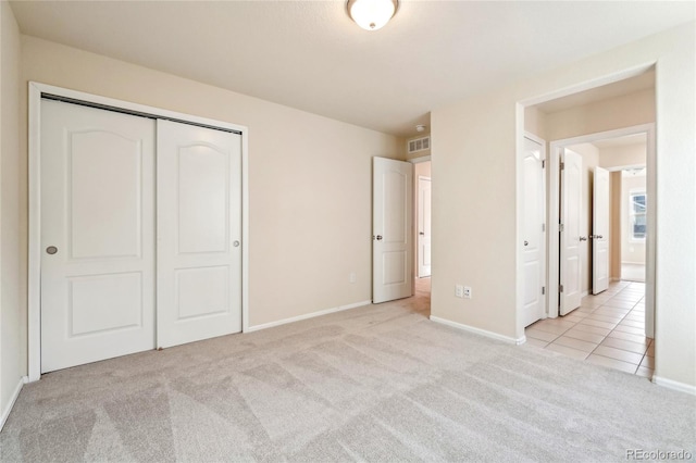 unfurnished bedroom with carpet, visible vents, baseboards, tile patterned flooring, and a closet