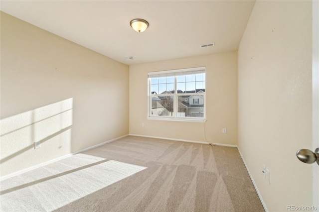 carpeted spare room featuring baseboards and visible vents