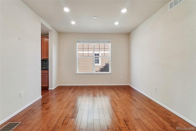 empty room featuring recessed lighting, visible vents, baseboards, and wood finished floors