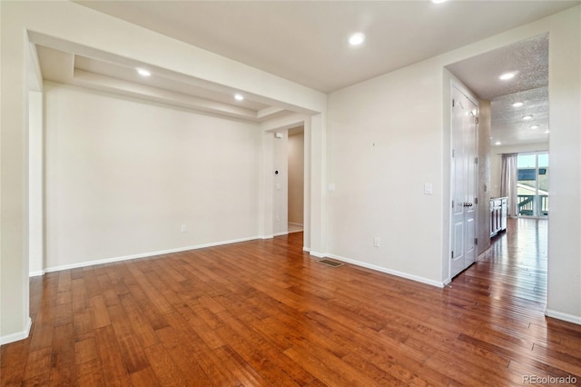 spare room with hardwood / wood-style floors, baseboards, and visible vents