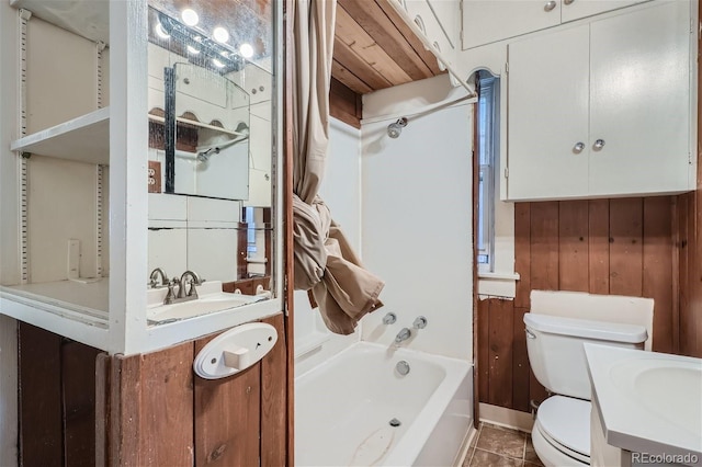 full bathroom featuring toilet, bathing tub / shower combination, wooden walls, tile patterned floors, and vanity