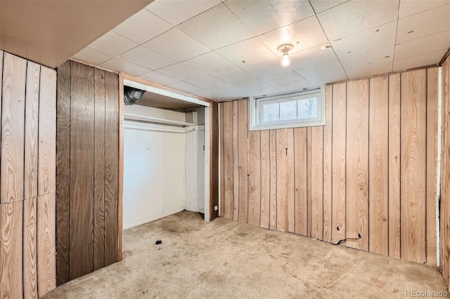 basement featuring carpet flooring and wooden walls