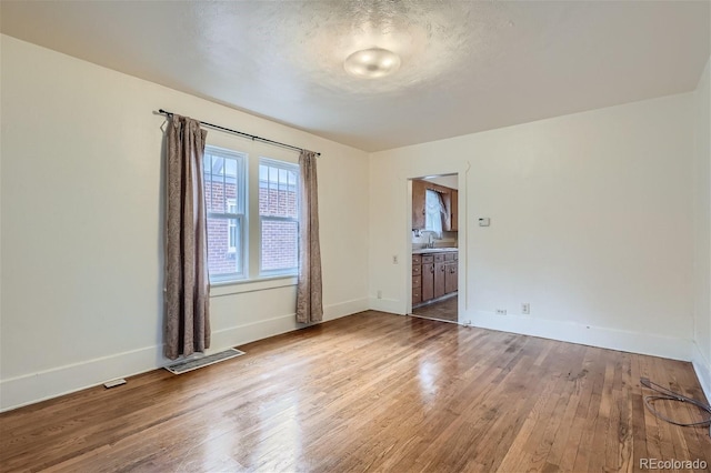 spare room with sink, hardwood / wood-style floors, and a textured ceiling