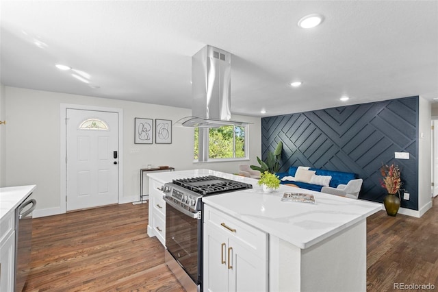 kitchen featuring appliances with stainless steel finishes, dark hardwood / wood-style flooring, island range hood, white cabinets, and a center island