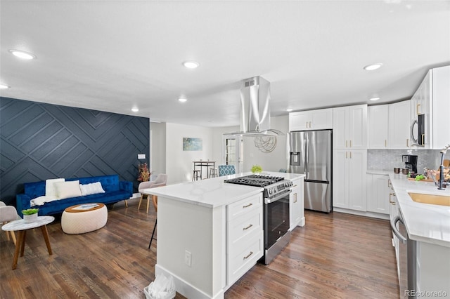 kitchen featuring dark wood-type flooring, white cabinets, a kitchen island, appliances with stainless steel finishes, and island range hood