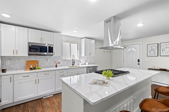 kitchen featuring island exhaust hood, white cabinetry, sink, and appliances with stainless steel finishes