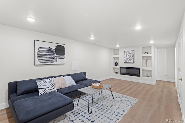 living room featuring built in features and light hardwood / wood-style floors