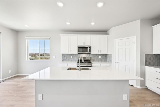 1957 S Coolidge Way, Aurora, CO 80018 - kitchen featuring stainless steel appliances, a sink, decorative backsplash, white cabinetry, and light wood-type flooring