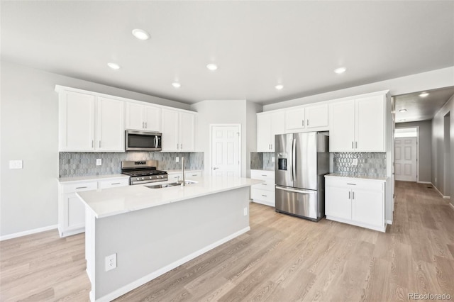 1957 S Coolidge Way, Aurora, CO 80018 - kitchen with stainless steel appliances, light wood-type flooring, backsplash, light countertops, and white cabinetry