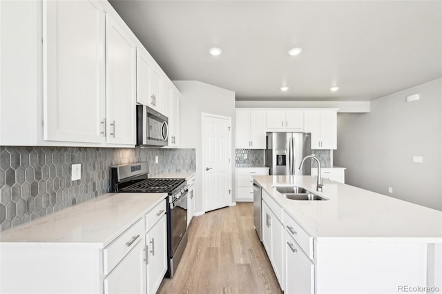 1957 S Coolidge Way, Aurora, CO 80018 - kitchen with appliances with stainless steel finishes, a sink, light wood-style floors, white cabinets, and decorative backsplash